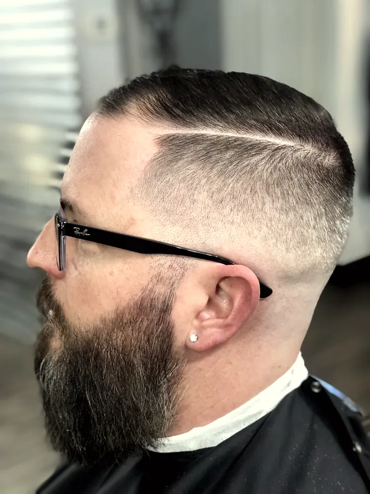 Skin fade with a hard part and a full shaped beard